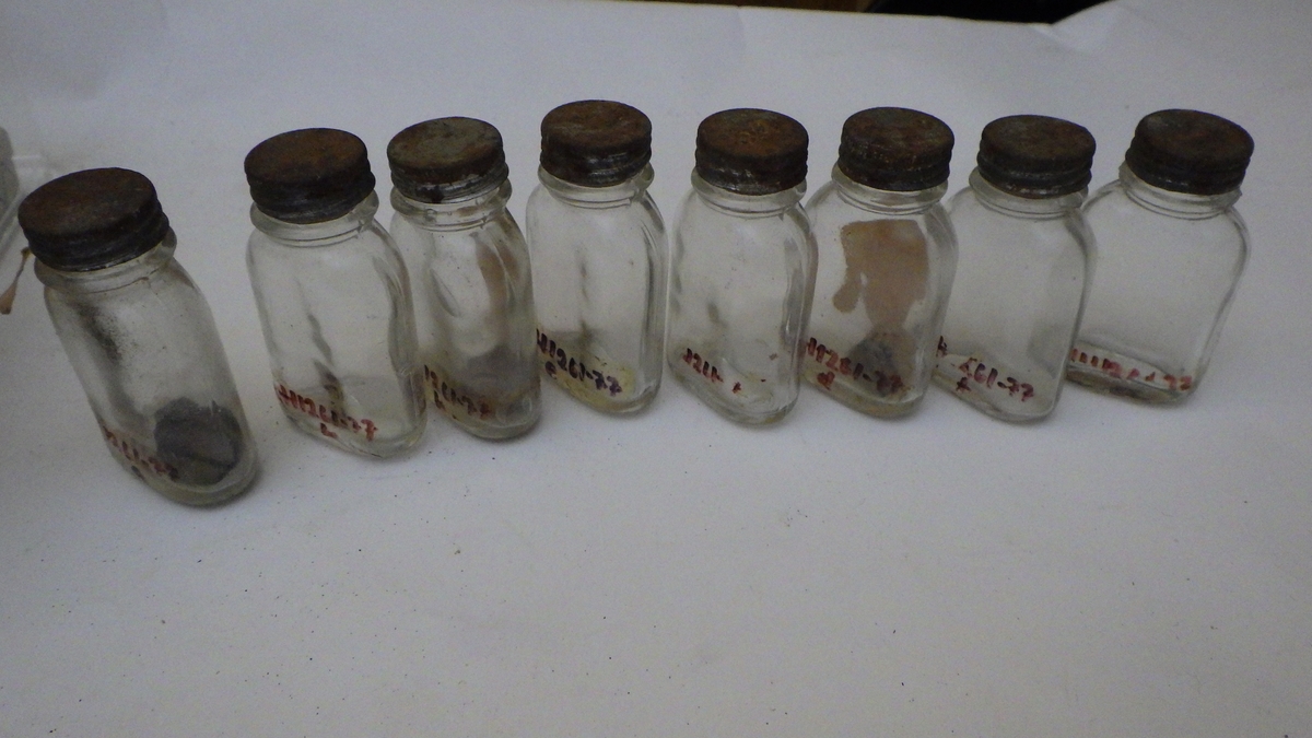 Flasker som har inneholdt romessens. Glass, med skrukork av metall. Rød etikett.