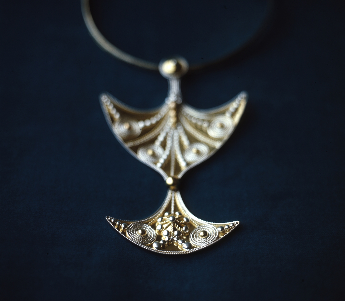 Halssmycke i guld av Rosa Taikon: "Somnakono towhér, Guldyxan". Smycket är dekorerat med silvergranulat och filigrantråd. Smycket finns idag i Röhsska museets samlingar.