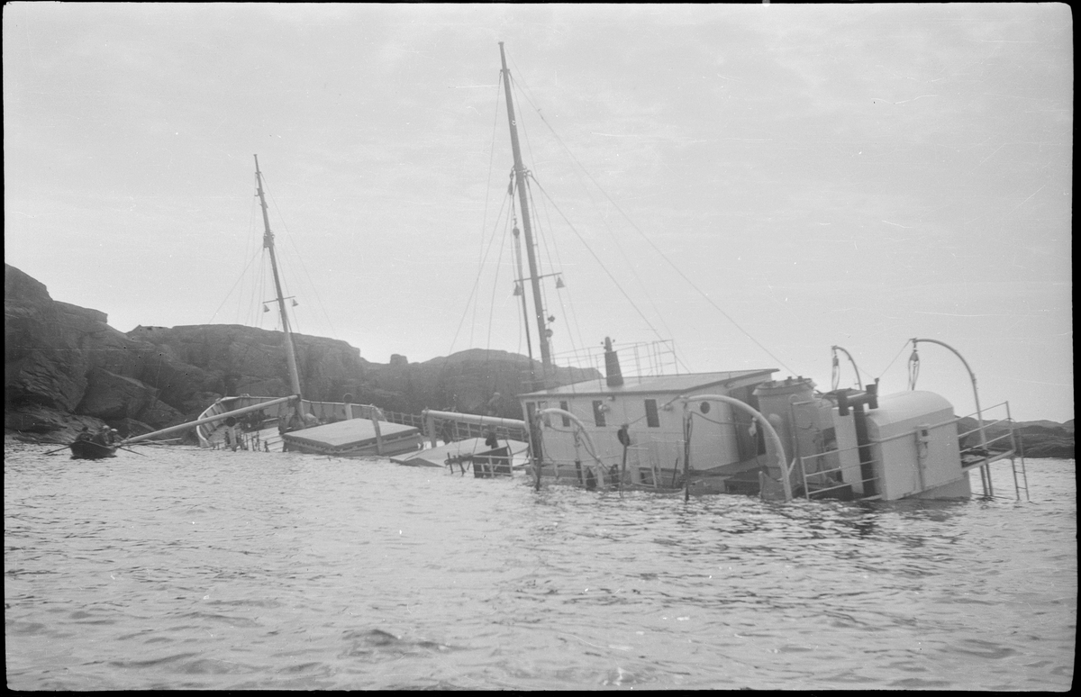 Lasteskipet "Rolfsøy" på grunn utenfor Egersund. Flere mindre båter er uten for å se og forankre skipet.