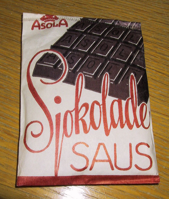 Pappeske med poser til koking av sjokoladesaus. Produsert av Asola Chokoladefabrikk a/s. Se også EKM-01820. 

