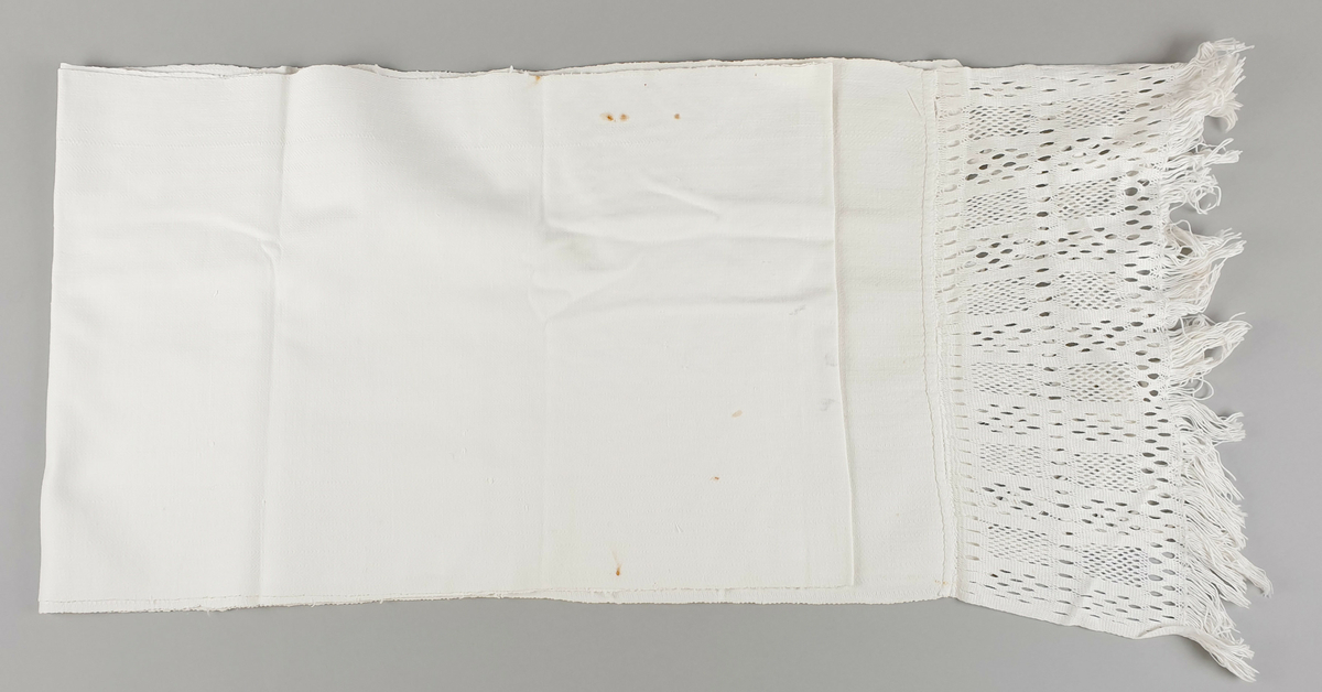 Langt pyntehåndkle av lin, med blondekant av sprang med ulike mønstre i hver ende. 