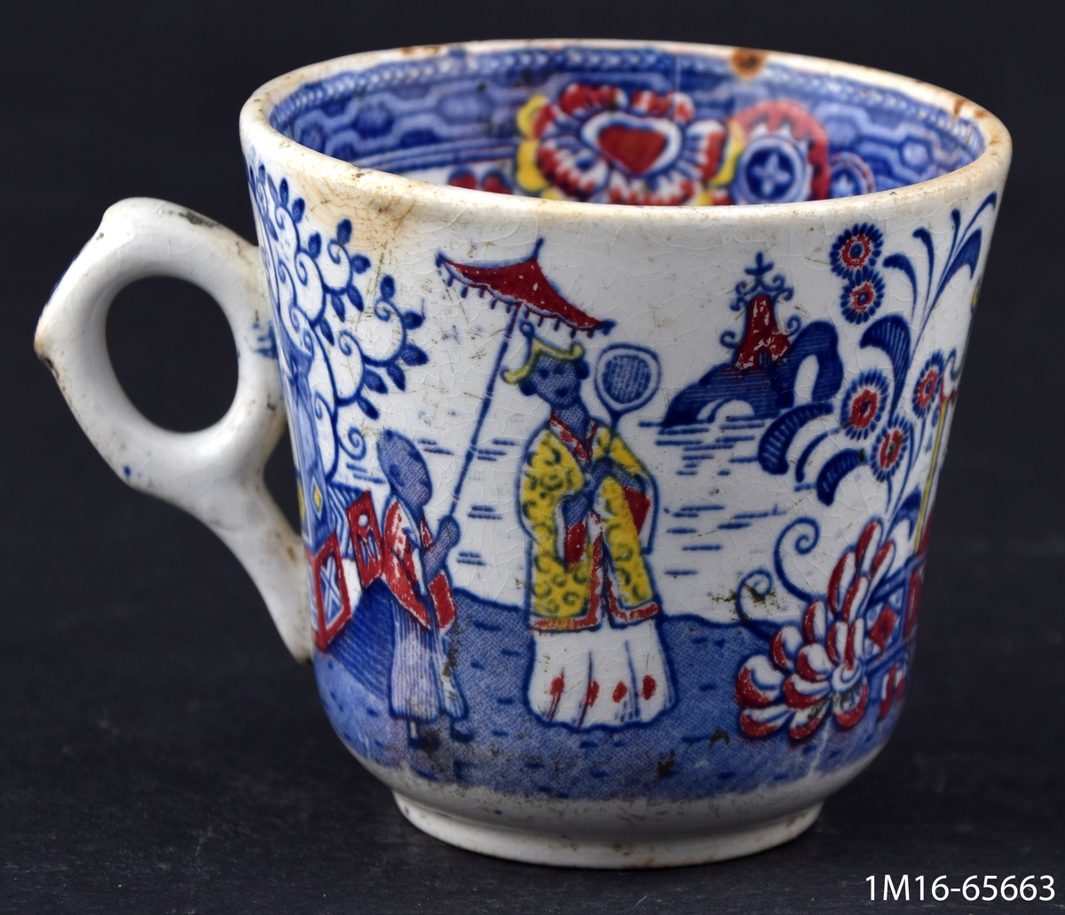 Kaffekopp, dekorerad med kineserier i blått, rött och gult, utanpå, inuti diverse ornament. Ett öra.