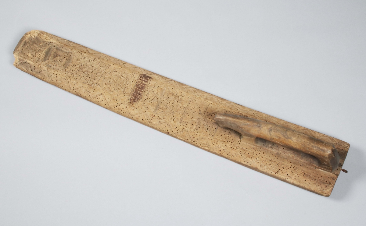 Mangelbräde i brunbetsat trä. Färgslitage, kraftigt maskstunget. Framändens kanter skadade. Hela ytan täckt med bladrosetter och rutor; längs de fasade kanterna zig-zagbård; handtag infällt i hästform; på namnskylten spår av brun färg. På ovansidan skuret: "BLMK ANO 1780" (Gunnar Blomgren)

Mangelbräde eller kavelbräde är ett redskap av trä som använts för mangling av textilier. Mangelbrädet användes tillsammans med en kavel, en slät rulle av trä. Den textil som skulle manglas, rullades upp på kaveln, på ett bord eller annat slätt underlag. Under hårt tryck, rullades kaveln med hjälp av mangelbrädet, fram och tillbaka över bordet. (Wikipedia)