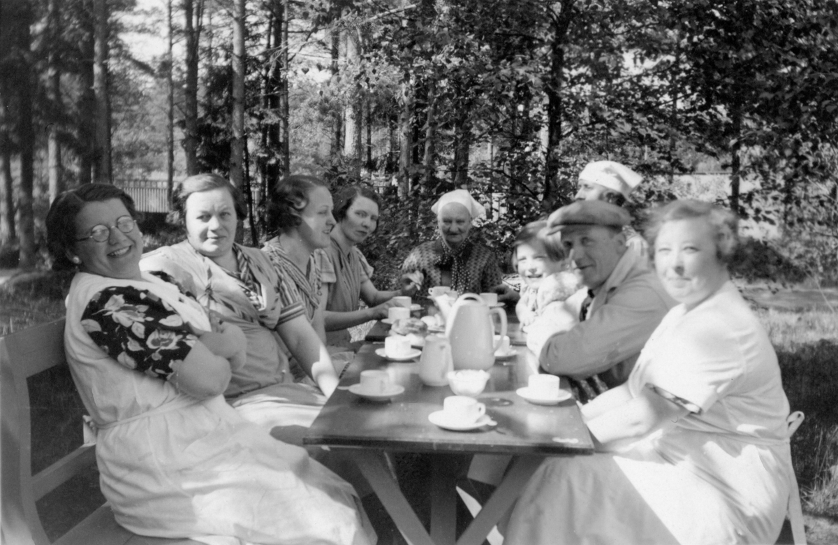 Foto på personalen i cafét i Folkets Park i Linköping sommaren 1937. De sitter utomhus vid ett bord med kaffekoppar på.