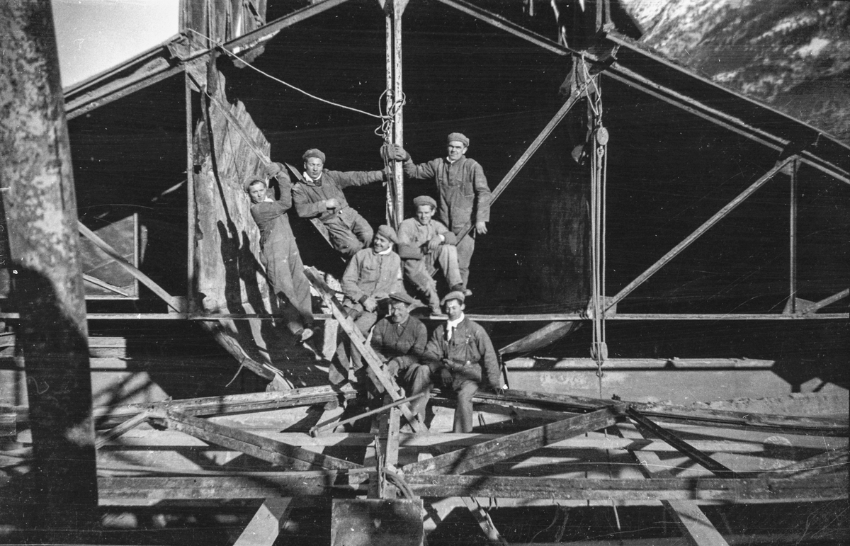 Arbeidslag med sju mann øvst på eit bygg på Odda Smelteverk.