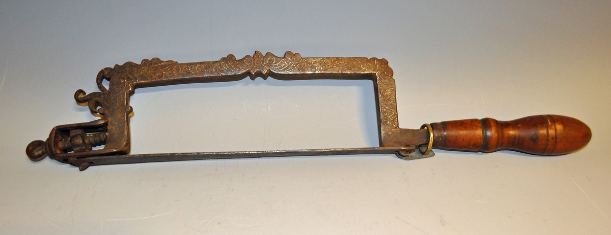 Fra protokollen: Haandsag af jern, særlig for tilvirkning af nøgler. Dreiet haandtak. Fin rokokkogravering og merket I. P. S. 1798. Dreiet haandtak.