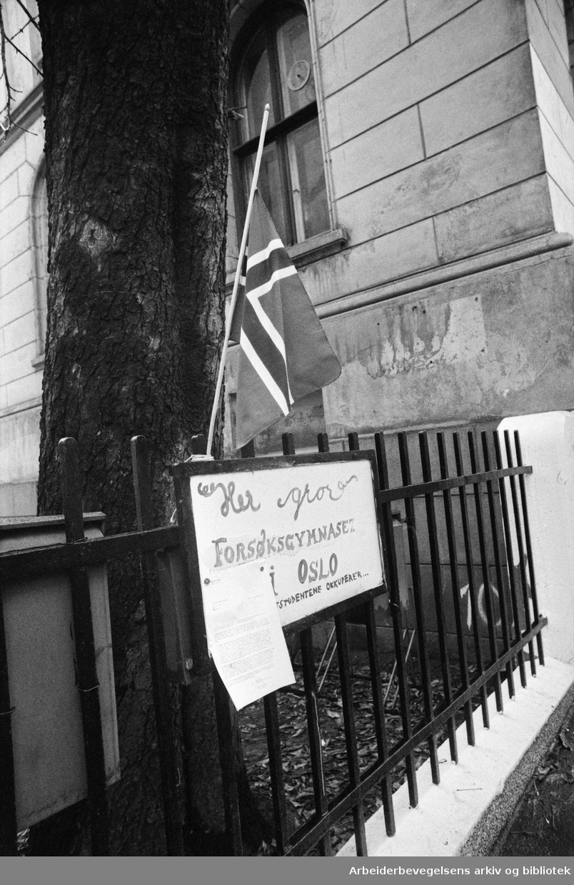 Elevene flagget på halv stang da Forsøksgymnaset flyttet fra Hammersborg skole til Tøyenhagen skole. Plakat med teksten: "Her gror Forsøksgymnaset i Oslo - Arkitektstudentene okkuperer.." November 1976.