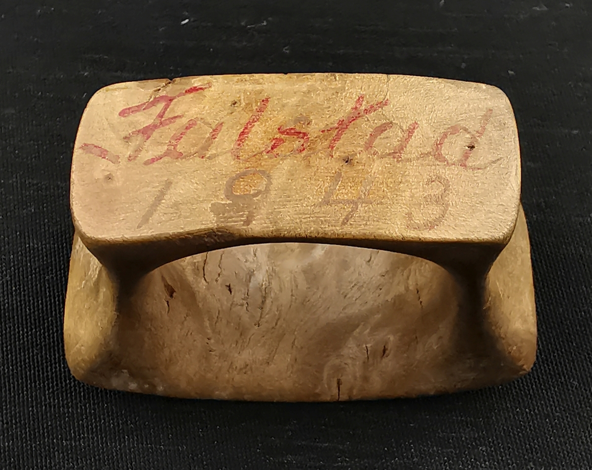 Utskåret ring (tørklering, skjerfring) i tre, gitt til Per Christoffersen (F. 1917, Mosjøen) under hans fangenskap på Falstad i 1943. Forsida er uten påskrift. På baksida er det skrevet "Falstad 1943".