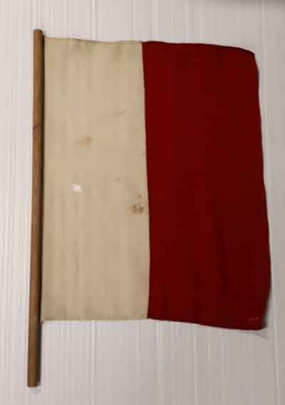 Semaforflagga av mindre storlek, med kapell. Röd av ylle. Kapellet av impregnerad segelduk. Har tillhört övningsfartyget af Chapman.
