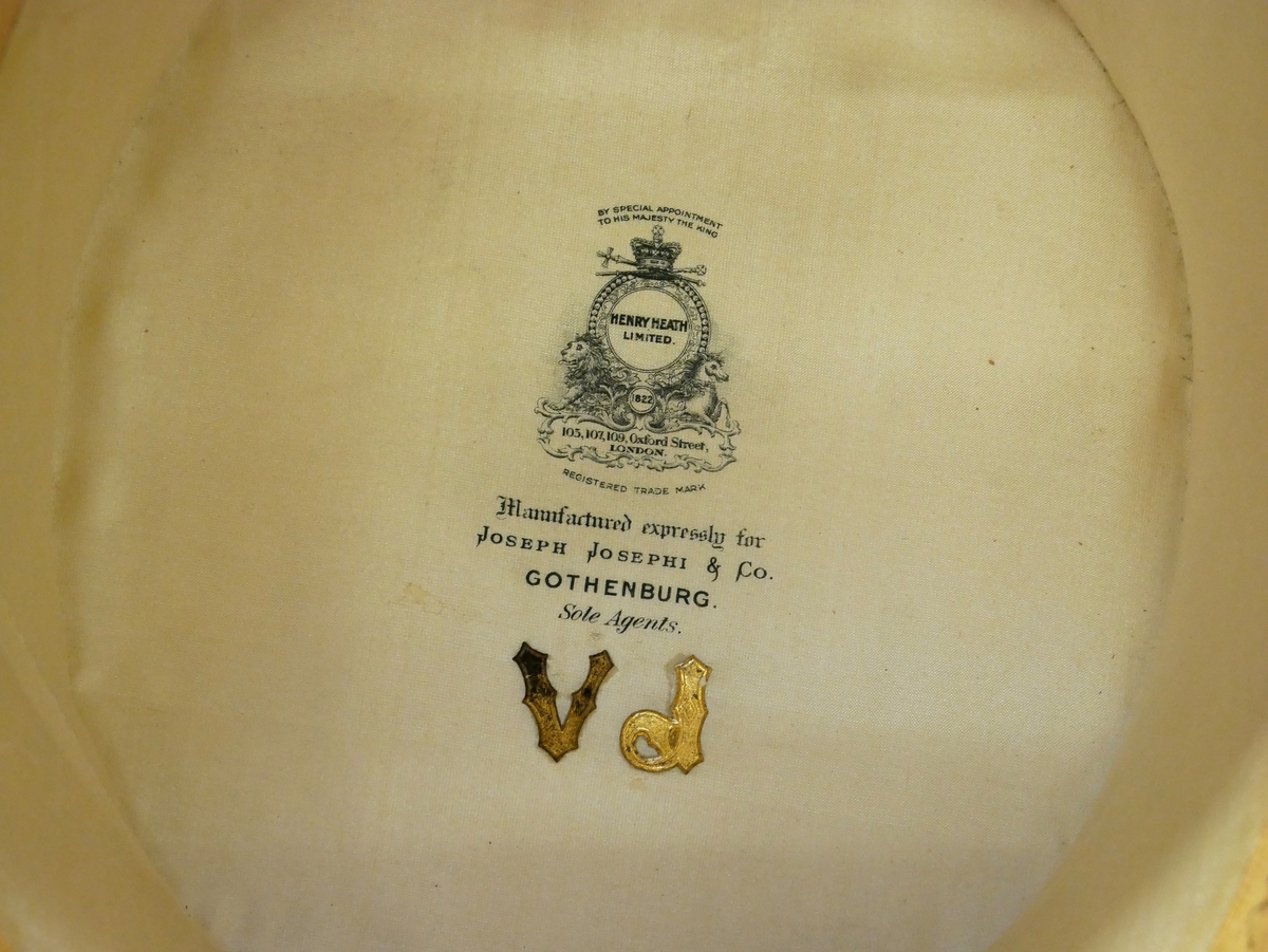 Hattask av läder innehållande hög hatt av svart silkesfälb och med brättet svagt uppvikt vid sidorna. I asken ligger även en lös läderbit från hattasken, en "kudde", fyra olika band till hattkullen samt en nyckel till hattask.

Asken är märkt med initialerna V.J samt märken från resor. 

Även insidan av hatten är märkt med V.J, i guld. Tillverkad av Henry Heath i London och såld av Joseph Josephi & Co i Göteborg.