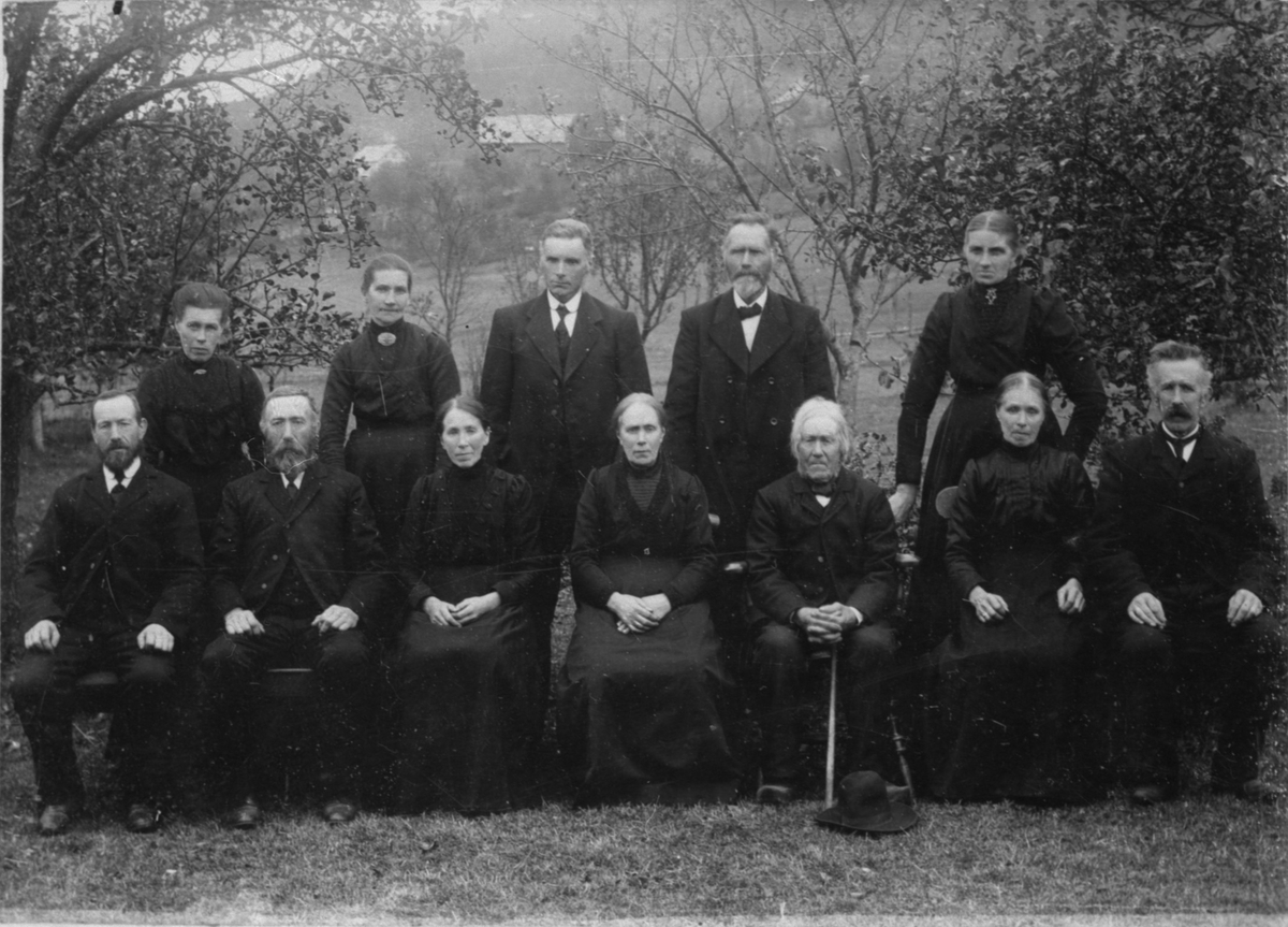 Familiebilete av Berge Larsen Espeland med born (sittande) og svigerborn (ståande bak) på Espeland i Ølensvåg, ca. 1915. Sitjande foran, frå venstre: Berge B. Espeland, Jørgen B. Eikeland (f. Espeland), Randi Espeland, Brynhild (kalt "Brølla") Velde (f. Espleand), Berge Larsen Espeland (far til dei sitjande), Elisabeth Dueland (f. Espeland) og Lars B. Espeland. Ståande bak, frå venstre: Marta Espeland (f. Heggebø) (gift med Berge B.), Eli Eikeland (gift med Jørgen), Torbjørn S. Espeland (gift med Randi), Sjur Velde (gift med Borghild) og Anna Malene Espeland (gift med Lars).