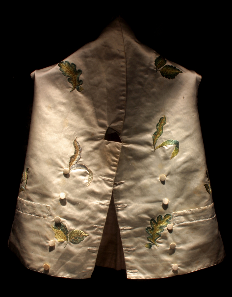 Foret silkevest med to lommer og broderier av eikeblad samt andre grønne planter. Fem knapper på hver side.