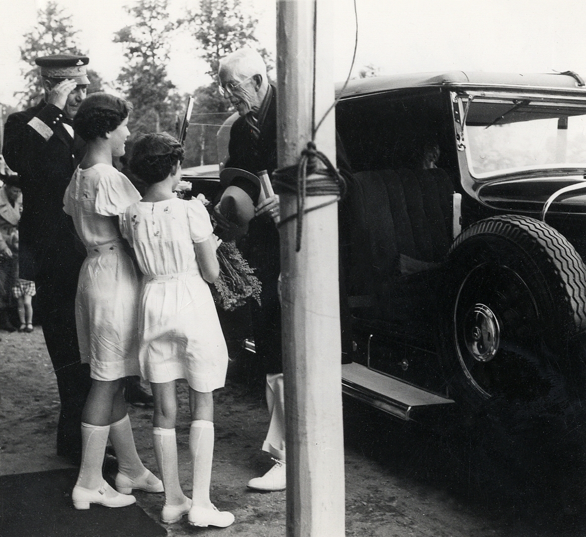 Kung Gustaf V vid invigningen av tennishallen (idrottshallen) i Växjö 1938. Majestätet får blommor vid ankomsten. Till vänster syns dåv. landshövding August Beskow.