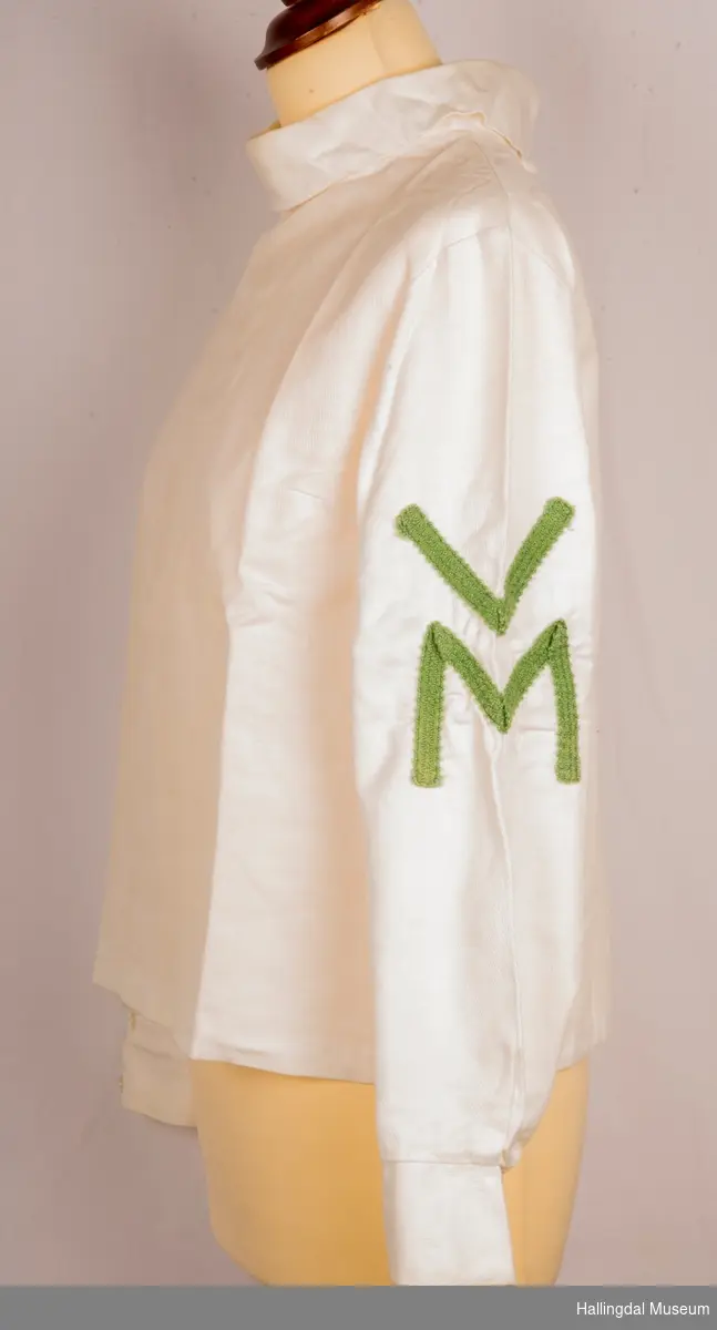 VM bluse som hører til drakt HFN 14365 a+b
60-tallet
Skjorte, bluse med høy krage, glidelås bak.