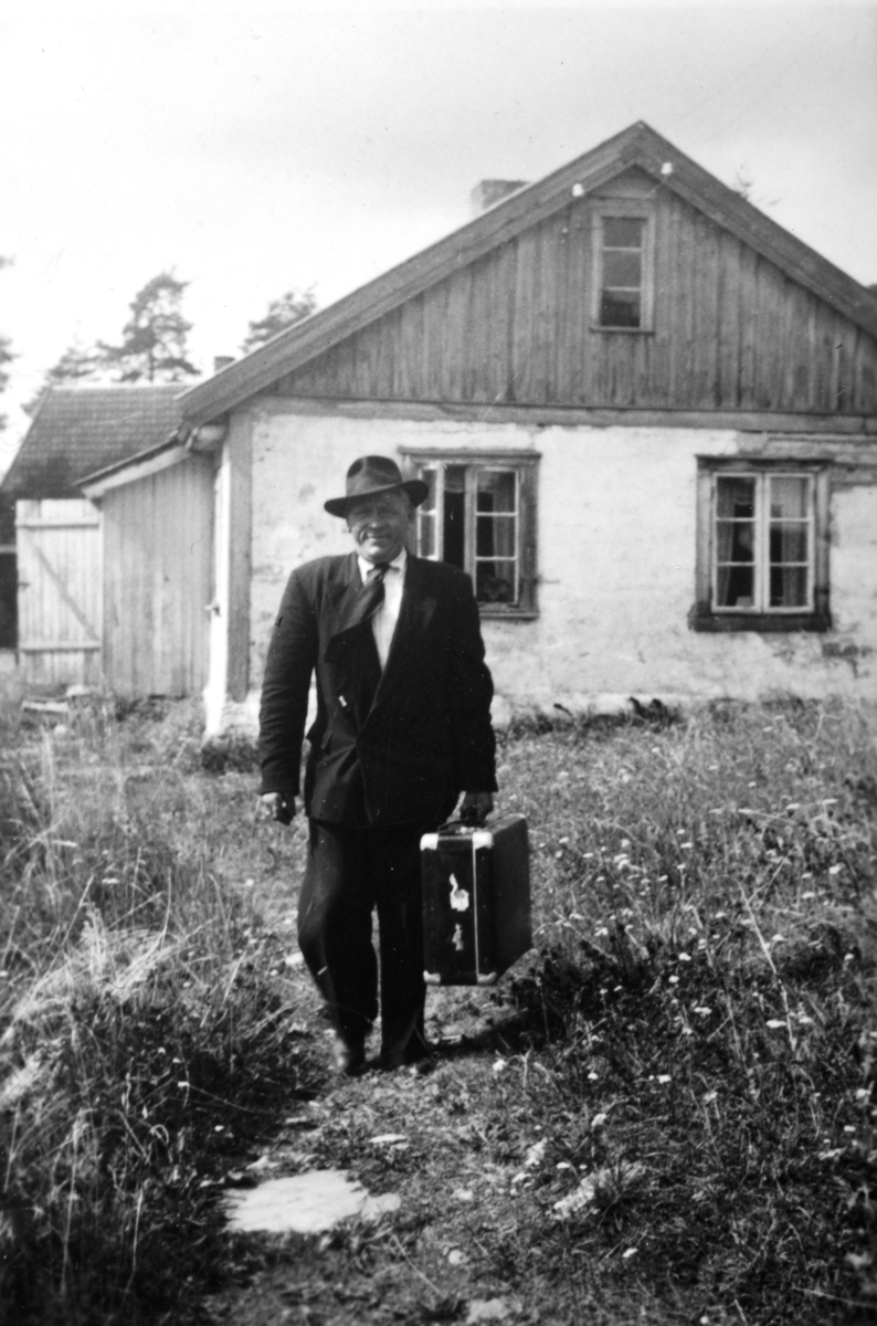 Hamar, Kvitbekken husmannplass på Martodden, Gustav Kjønningsberg (1897-), hatt, dress, koffert, husene er rappet,