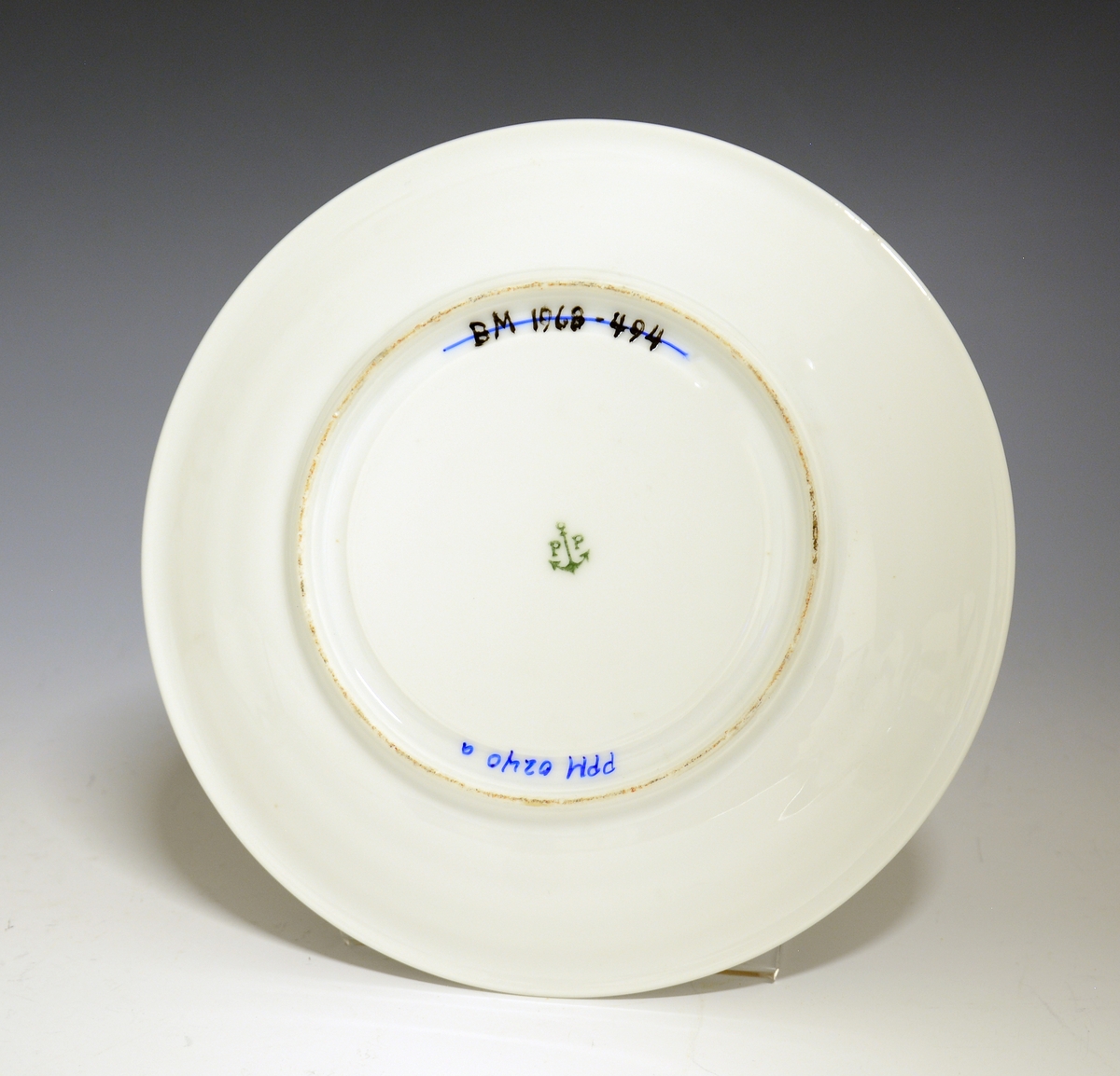 Prot: Smørdåse av porselen. Sylindrisk beholder fast på skål med fire konkave, sirkulære avtrappinger til en utbrettet kant. Halvkuleformet lokk med avtrappet topp som har halvkuleformet lokkgrep. Hvit glasur uten dekor. Nora Gulbrandsens modell 1875.