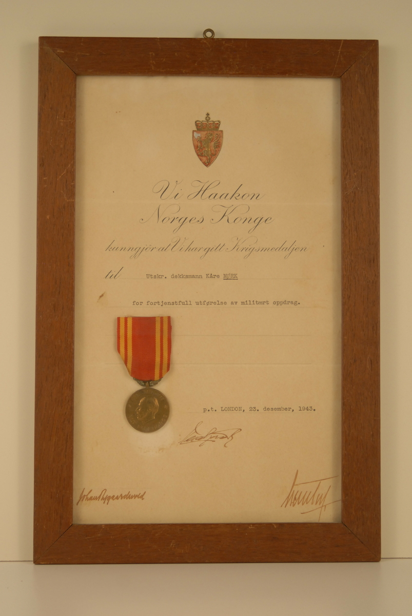 Den norske løve med krune øverst på diplomen. Medaljen syner Kong Haakon i profil.