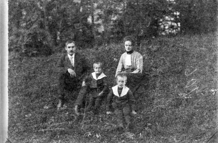 En kvinna, en man och två små pojkar sitter in en grässlänt. Sannolikt en familj.
