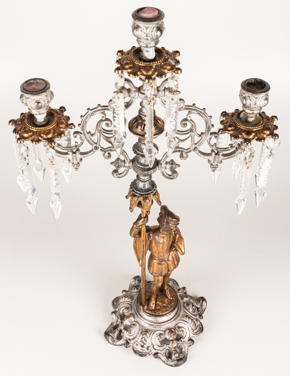 Kandelaber, en i ett par, av bronserat järn, tre ljuspipor med prismor.
