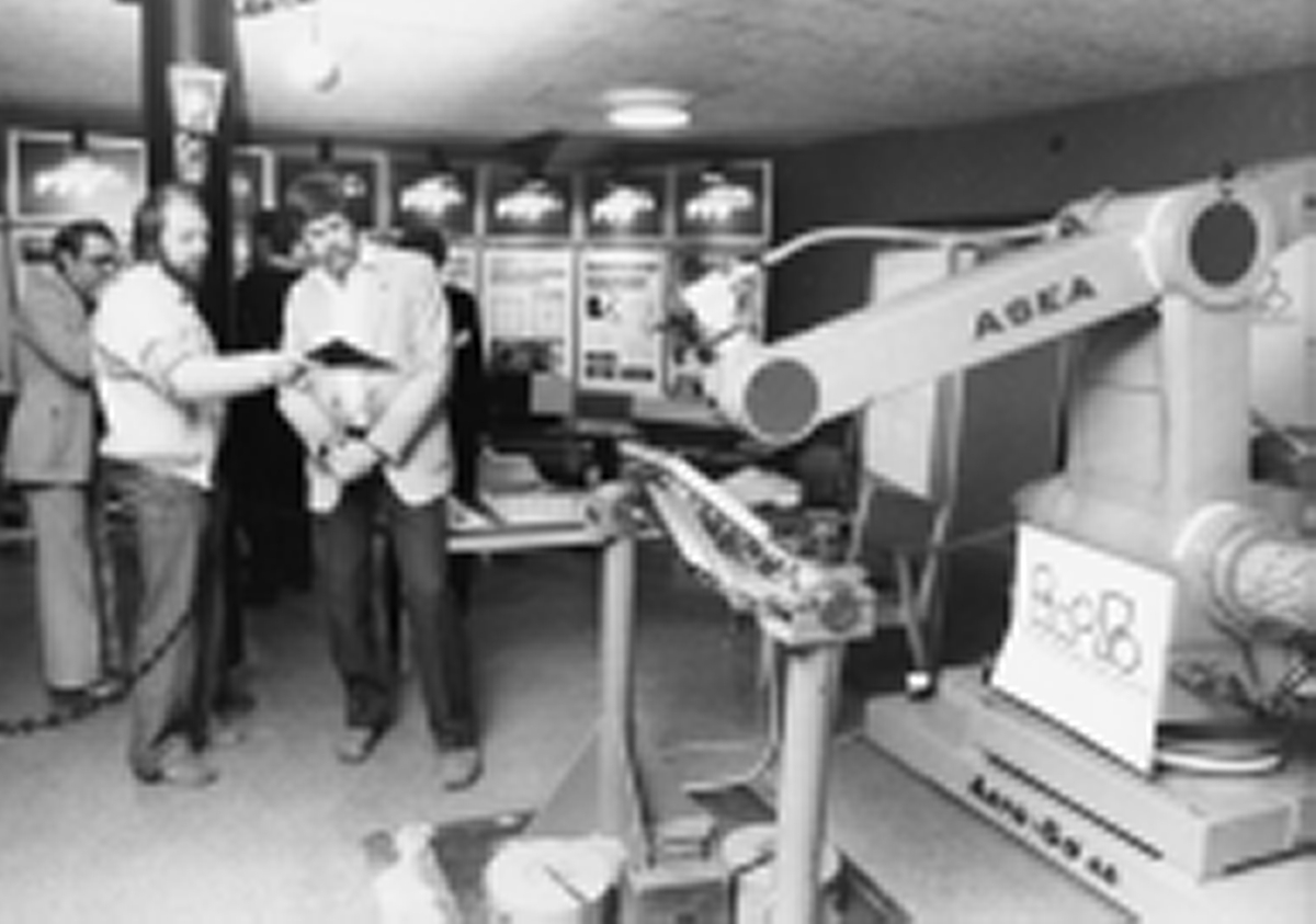 Bild i Cupolen under Tekniska Träffen i Linköping den 17-18 mars 1983. Teknikutställning. I förgrunden en maskin från ASEA. Två män studerar den.