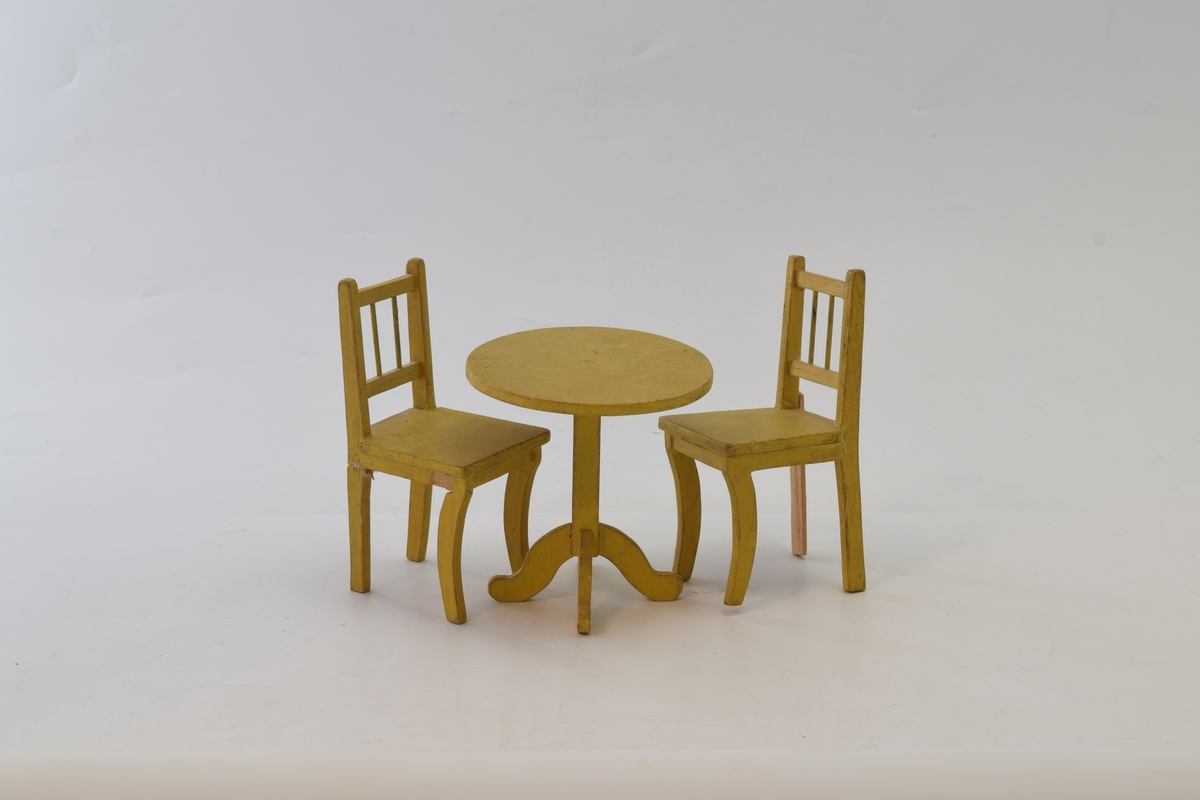 Spisestuemøblement i tre. Detaljrikt arbeid med avrundede bordbein og kurvede bein på stolene. Den ene stolen ahr fått et nytt bakbein.