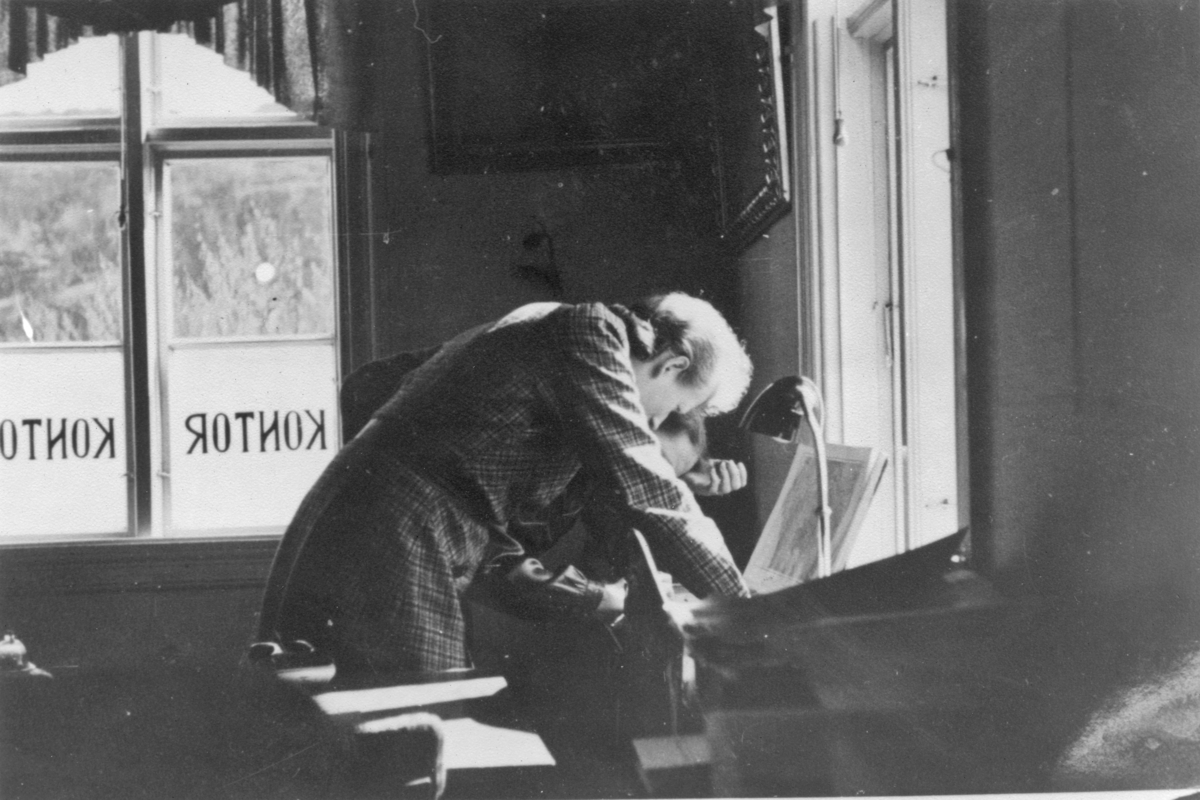 Fayancefabrikkens kontor, ca. 1950. Ingeborg Feyling studerer atlaset.