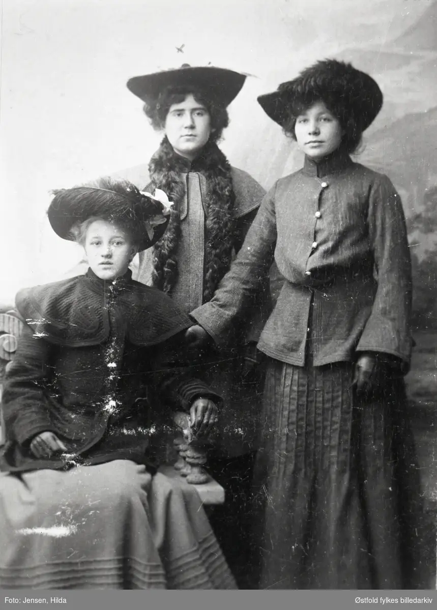 Gruppeportrett av tre  ukjente damer med hatt og kåpe, visittkort, atelierfoto.