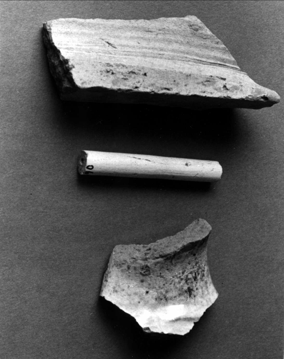 Fragment av oglaserat kakel, gulglaserad keramik (B-gods) och skaft av kritpipa.