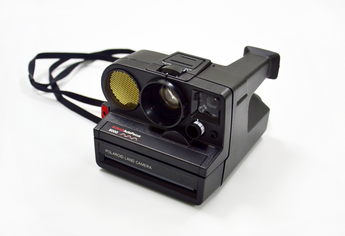 Polaroidkamera i sort plast med stativ, produsert på slutten av 1970-tallet, antagelig 1979. Blitzen mangler. Filmtypen som ble brukt (og som fortsatt kan skaffes) var av type SX-70. Objektivet skal ha tre linser (114 mm). Avstanden ble gjort automatisk ved av et ultralydsignal ble rettet mot motivet som sendte en ekkolyd tilbake til kameraet hvor avstanden så ble utregnet automatisk - antagelig derfor den har "Sonar" i navnet. Vet ikke om kameraet fortsatt virker. Ei tynn sort reim til å feste kameraet rundt halsen.