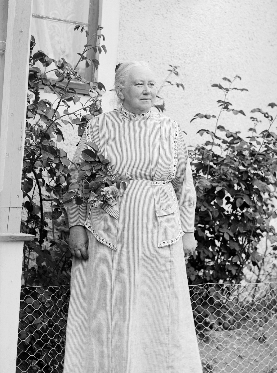 Enligt uppgift ska kvinnan på fotot föreställa Eva Laura Charlotta Lind, född Aspling. År 1888 gifte hon sig med kyrkoherde Karl Johan Lind och paret var bosatta i kyrkoherdebostaden Korsnäs i Sankt Anna under åren 1907-1919. Dock är det inte denna bostad hon står invid på bilden.