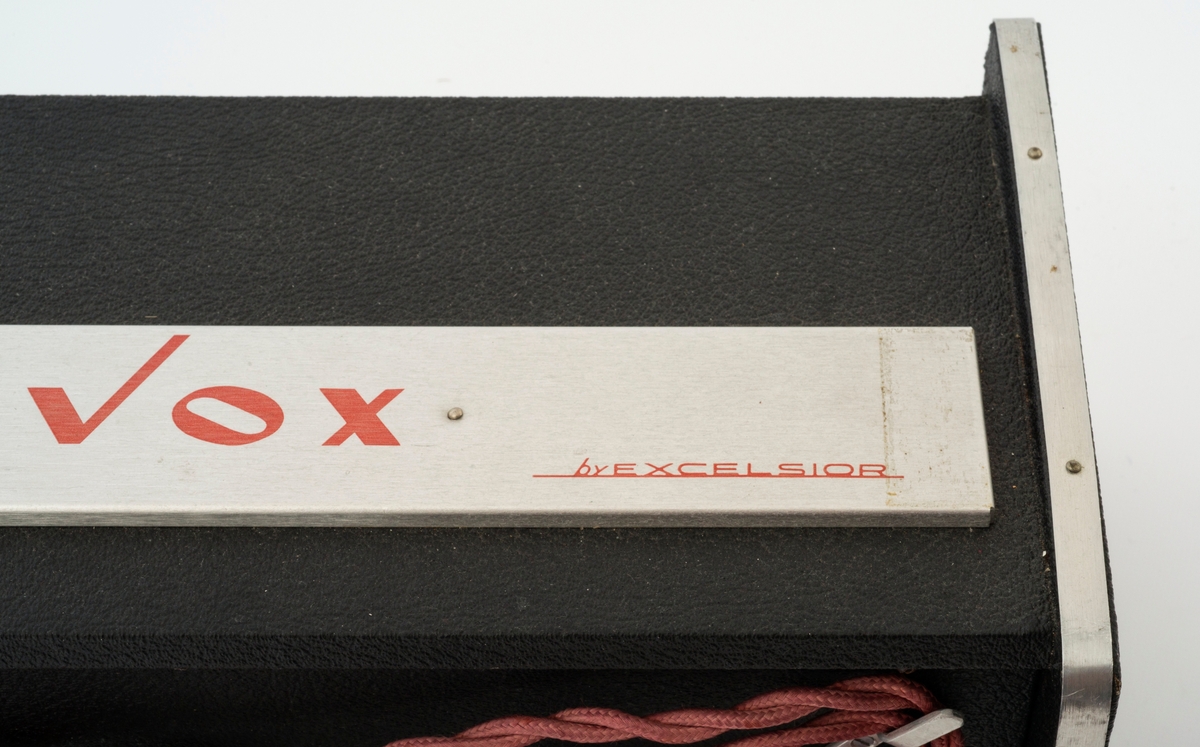 Excelsior Genavox Solid State 1500. Lydforvrenger til trekkspill med en mengde effekter. Tilkoblingsmulighet til trekkspill, forsterker og fotpedal. På baksida henger en bagasjelapp.