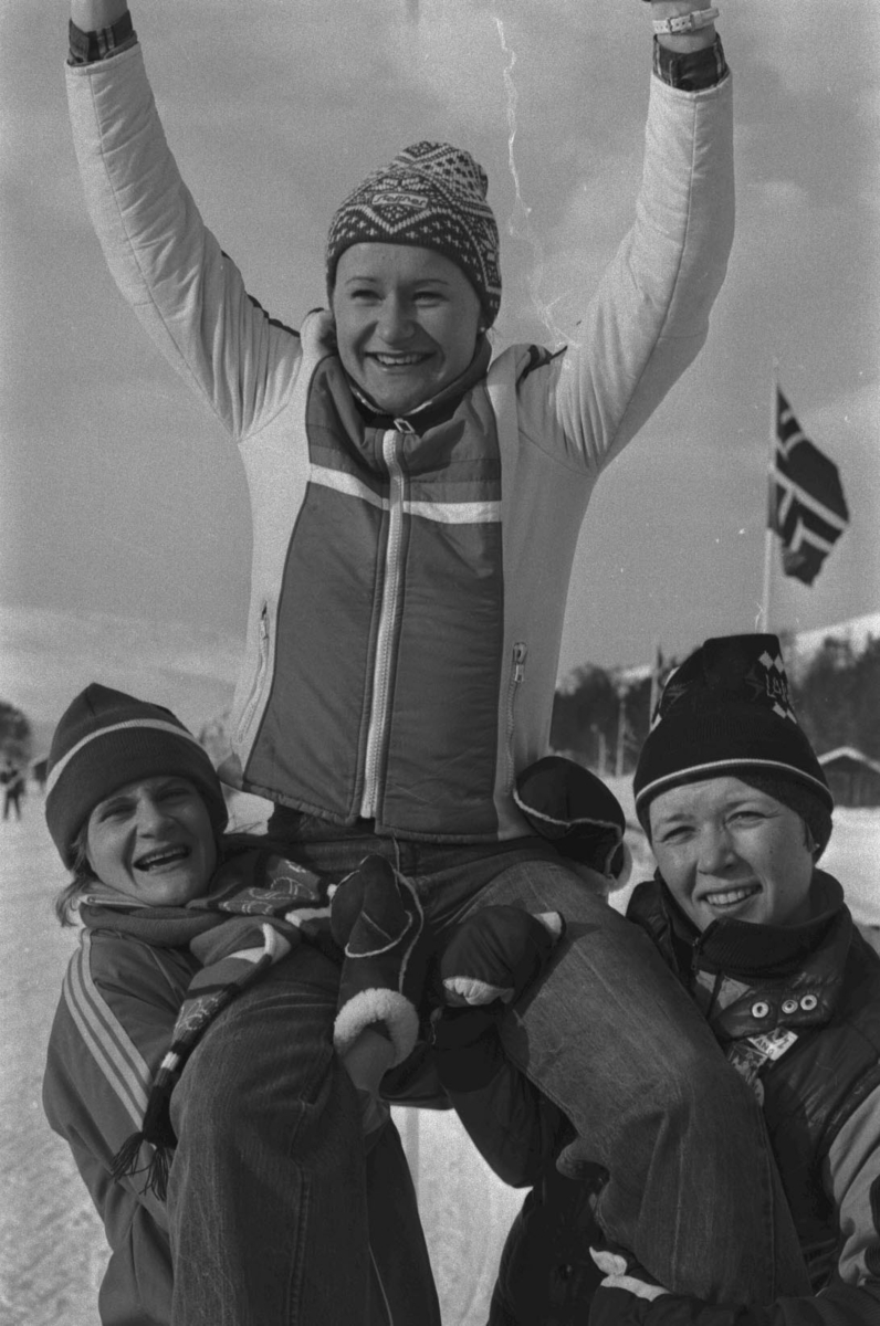 Jublende dame bæres av to kvinner, Skiløper