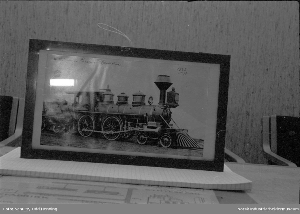Fotografi av gammelt prærielokomotiv i ramme, som står på en notisblokk.