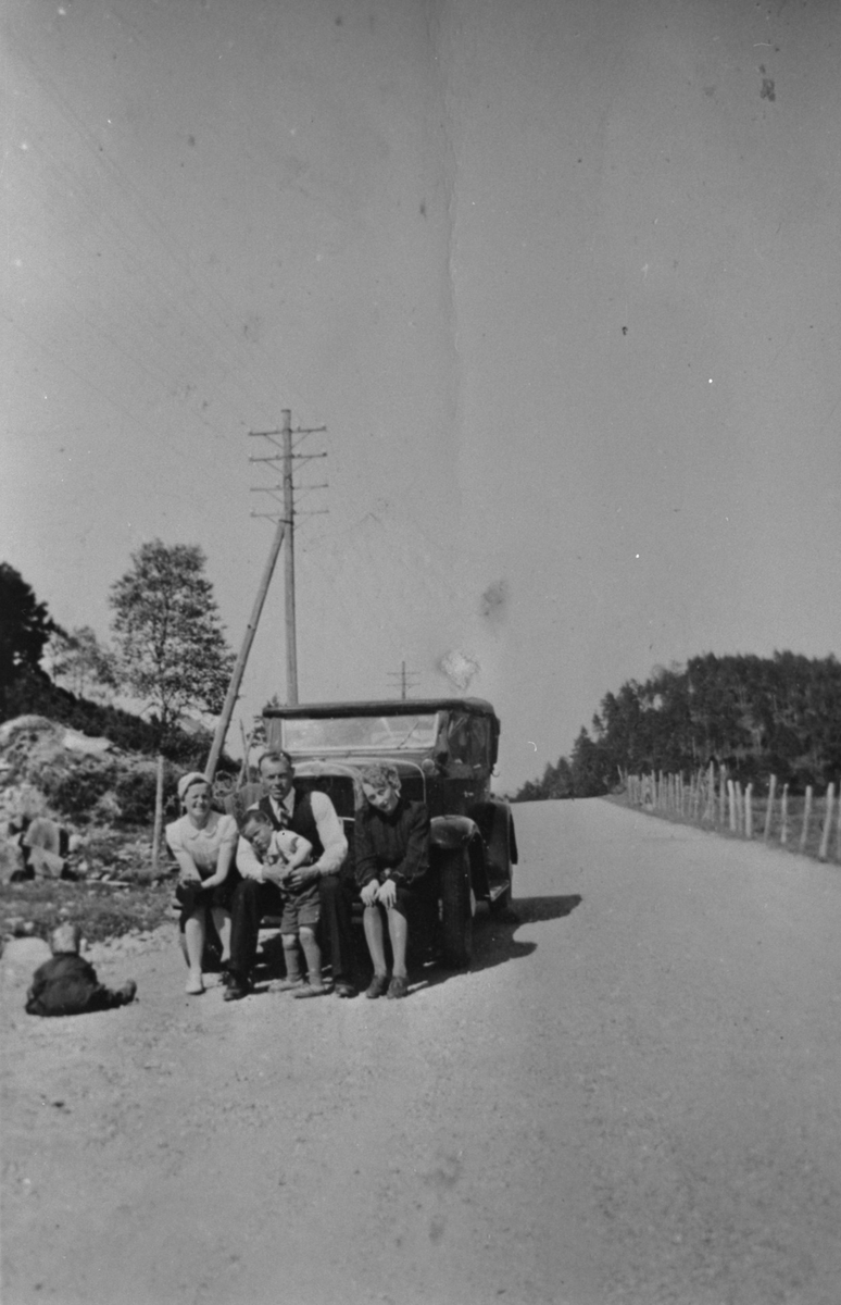 På tur ved Fikse i Ølen, ca. 1940. Bilen er ein Chevrolet 1931. Frå venstre: Anne Haugland, Jørgen H. Haugland, Harald Haugland (på fanget til Jørgen) og Marie Aarro.