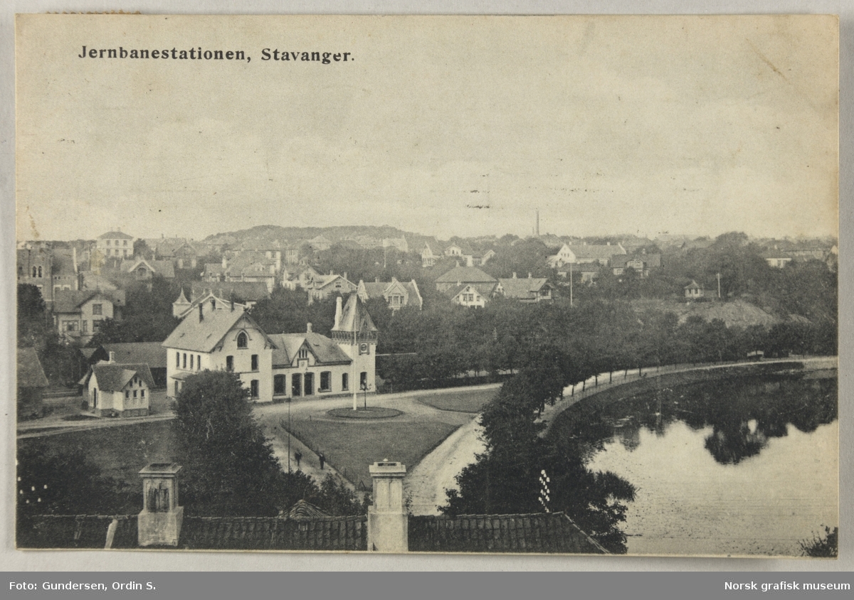 Postkort med bilde av jernbanestasjonen i Stavanger, sett fra sør. Til høyre er Breiavatnet.