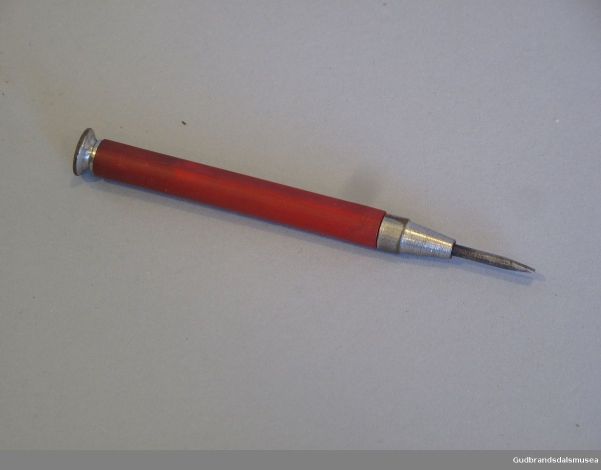 Skrujern brukt på Balopticon Model C. Produsert i USA fra rundt 1910 av Bausch & Lomb. Har form som en liten blyant med rødt palsskaft.