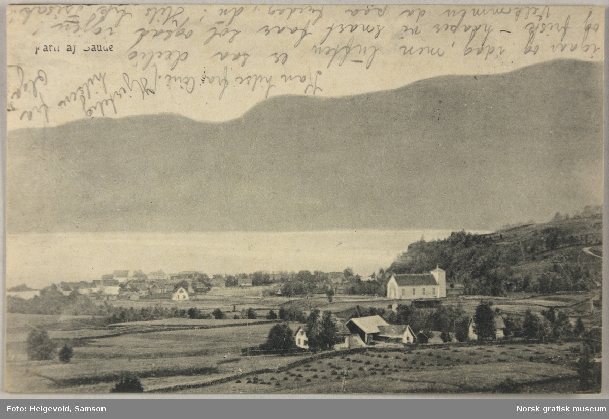 Postkort med bilde fra Sauda. Kirka og noen gårder ligger øverst i bygda, med flere hus ned mot fjorden.