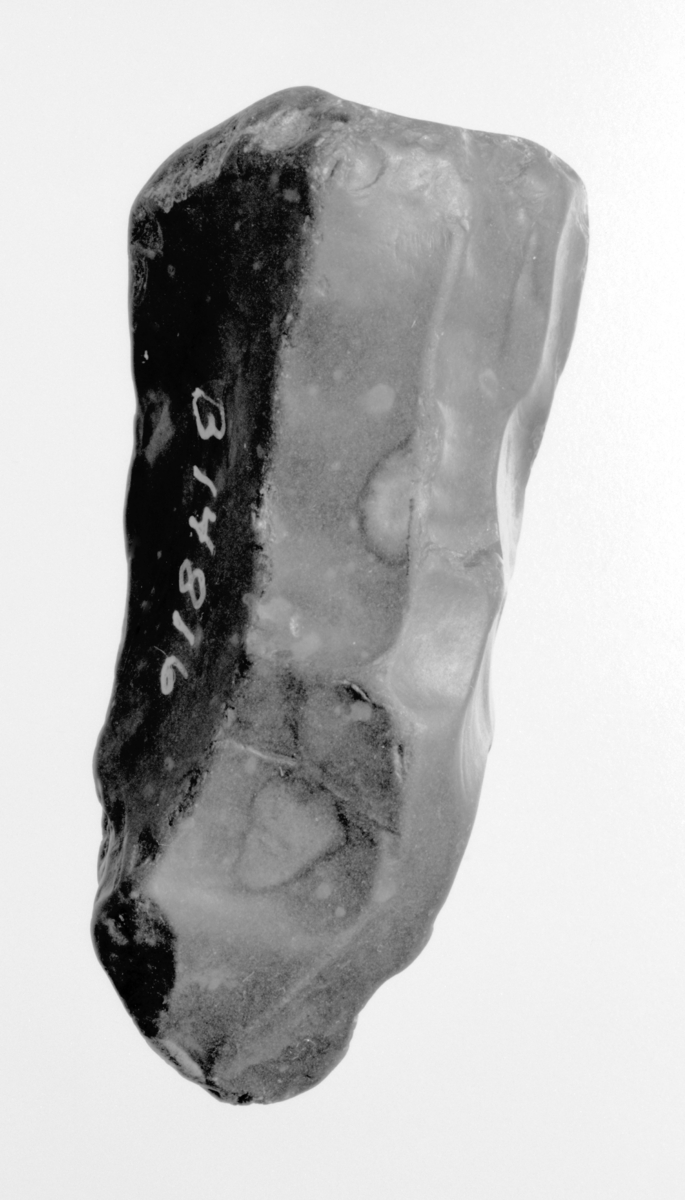 Kjerne av mørk grå flint, virker vannrullet, spor av cortex. L. 5,3 cm, st.br 2,4 cm.
