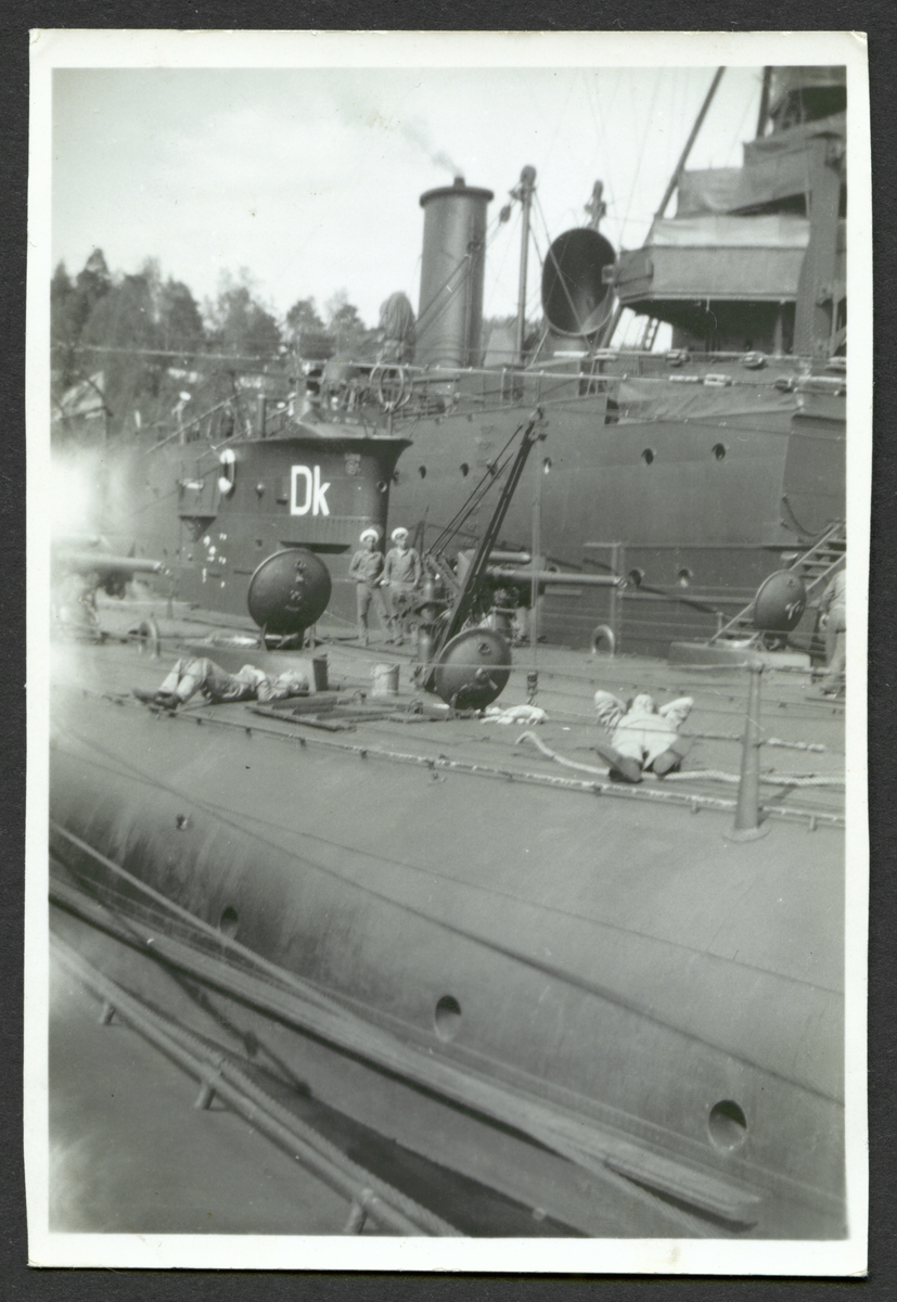 Bilden visar sjömän som tar en paus på däck av ett ubåt som ligger förtöjt med andra örlogsfartyg.