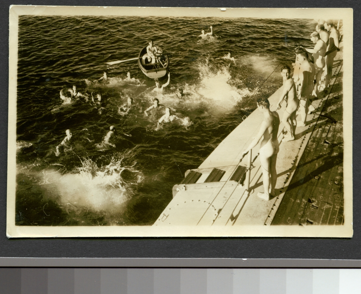 Bilden visar besättningen av en ubåt som badar i havet. En del av männen står avklädd på däcket.