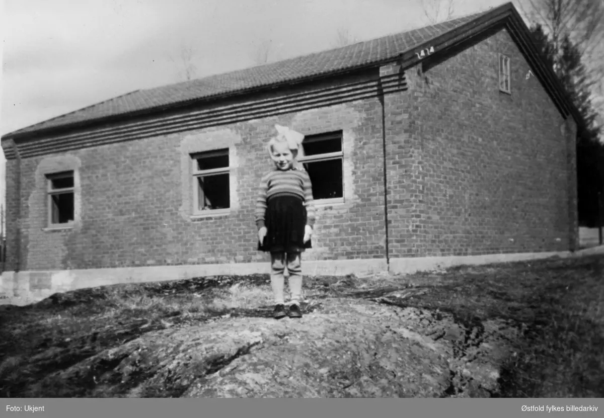 Torunn Heed F. 1941 (gift Øhrn) foran det gamle elektrisitetsverket, ca- 1945-46. tHuset er fra før 1940. Tyskerne bruket huset til stall under 2. verdenskrig.