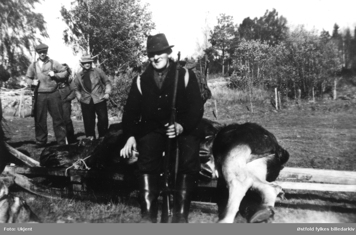Julius Bergby på elgjakt. Han sitter på elgen som han har skutt. De to andre jegerne er fra venstre: Bjørgan Belsby, Carl Caspersen Tomte. Bildet er tatt i 1947 på Knatterud i Varteig. Elgen ble skutt på Fosseiene (Knatterudfjellet). Elgen ligger på en "langslae"/slede.