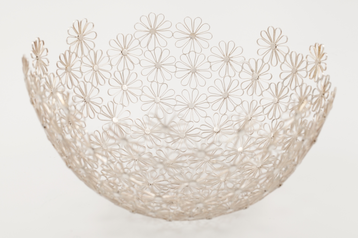 Halvkuleformet bolle i sølvfiligran, som danner et nettverk bestående av stiliserte blomsterformer.