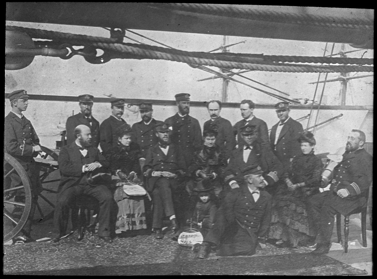 Bilden förställer fregatten Vanadis sjöofficerare och några kvinnor i civila kläder som har samlats för en gruppfoto ombord på fartyget.