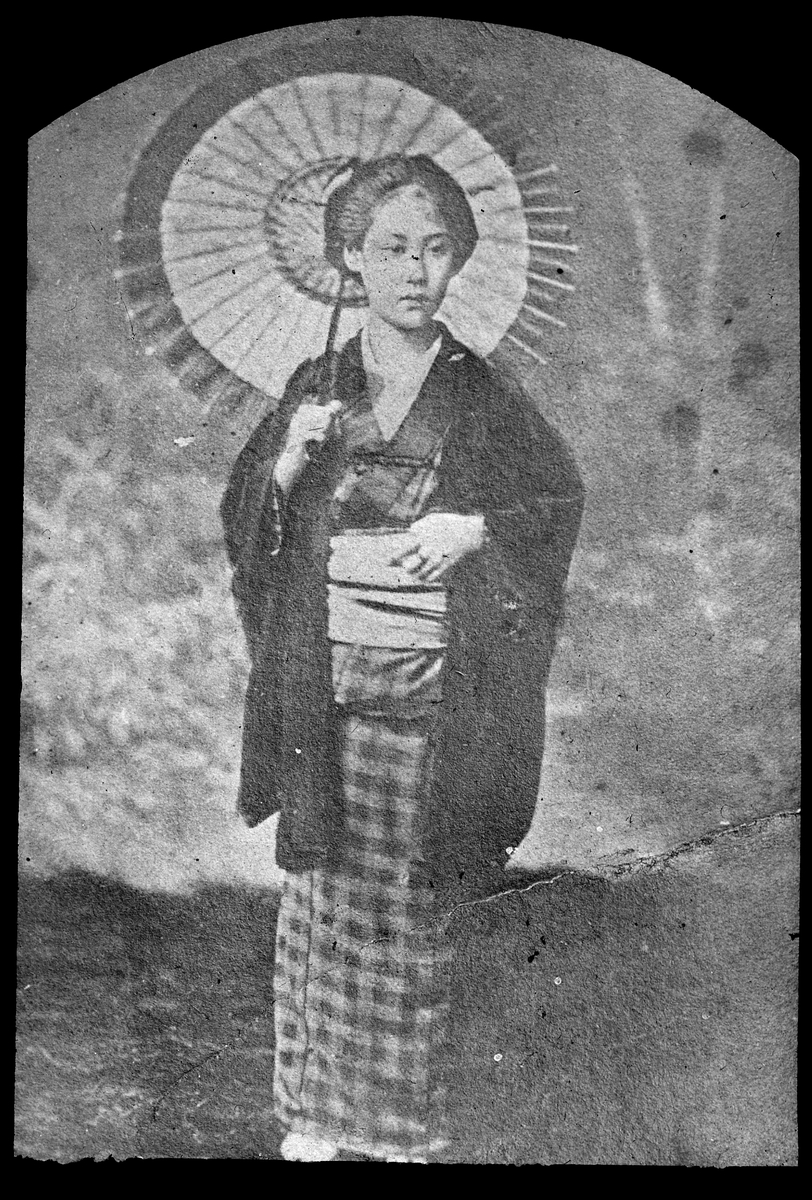 Bilden visar en japanskkvinna i en traditionell dräkt med parasol.