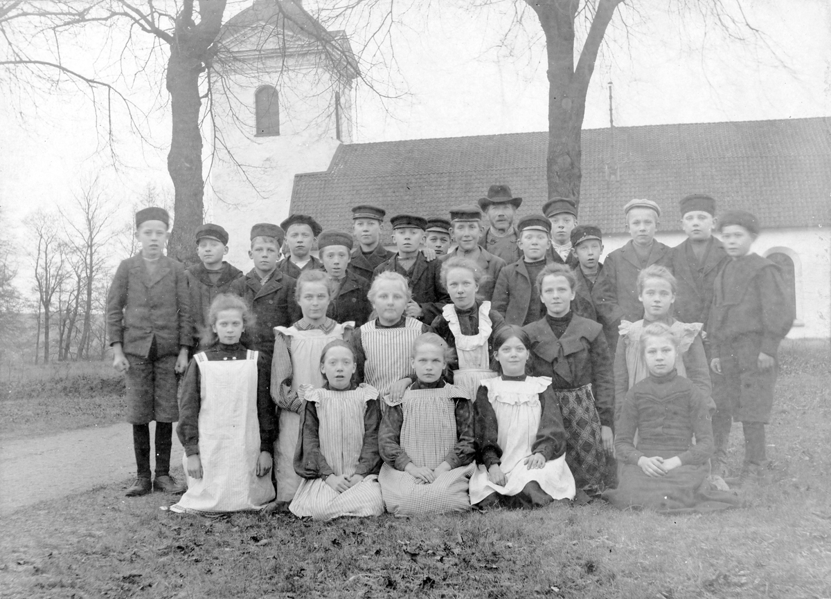 Skolklass, pojkar och flickor med sin lärare från landsförsamlingens folkskola, Klockarebolet, (sen Afzeliiskolan) utanför Landskyrkan.