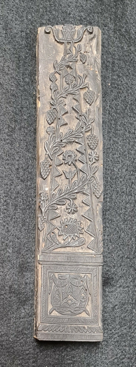 Färgplatta eller tryckstock i trä. Motiv är en blomsterarrangemang i kruka.
Ingår i en samling färgtryckplattor från Sundals Ryr.