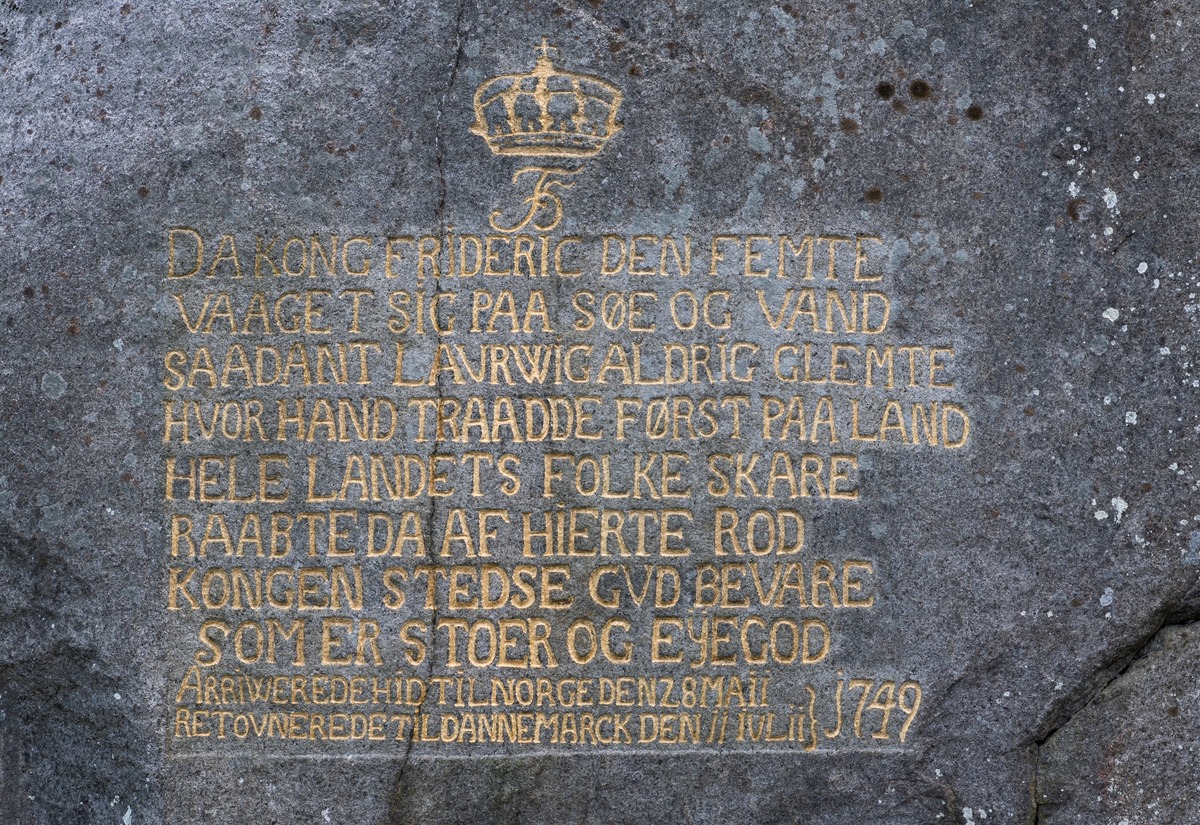En av flere inskripsjoner i berget ved Herregårdsbakken i Larvik, innhogd til minne om kongebesøk i byen. Dette er en av to tekster fra Fredrik 5.s besøk i 1749. Besøket er omtalt slik på ei informasjonstavle på stedet: «KONG FREDERIK V. Den siste enevoldskongen som besøkte Larvik overtok tronen bare 23 år gammel, i 1746. Tre år senere foretok Frederik V den tradisjonelle norgesreisen. Ferdinand Anton Danneskjold-Laurvig maatte for andre gang i sin tid klargjøre Herregården for majesteten. Til kongens ære ble det også bygd en to etasjer høy provisorisk festsal i hagen. Greven og grevinnen var til stede da kongen ankom Larvik 28. mai 1749. Han ble hyllet med en parade der byens borgere deltok under borgerfanen med borgermusikken i spissen. Deretter fulgte arbeiderne ved grevens jernverk, gruver og sagbruk under ledelse av forvaltere og betjenter. Etter en rundreise på Østlandet returnerte kongen til Danmark 11. juli.» Hvor mye arbeid greven la i å klargjøre herregården kan man vel tro mangt om, men det var sikkert viktig for ham at han og det lokalsamfunnet Ferdinand Anton Danneskjold-Laurvig administerte og hentet sine inntekter fra gjorde et godt inntrykk på den prestisjetunge gjesten. Dette er en av to inskripsjoner fra Fredrik 5.s besøk (den andre befinner seg litt lengre nede i bakken). Den lyder slik:

«DA KONG FRIDERIC DEN FEMTE
VAAGET SIG PAA SØE OG VAND
SAADANT LAURWIG ALDRIG GLEMTE
HVOR HAN TRAADDE FØRST PAA LAND
HELE LANDETS FOLKESKARE
RAABTE DA AF HIERTE ROD
KONGEN STEDSE GVD BEVARE
SOM ER STOER OG EYEGOD
ARRIWEREDE HID TIL NORGE DEN 28. MAII
RETOVNEREDE TIL DANNEMACK DEN 11. JULII 1749»