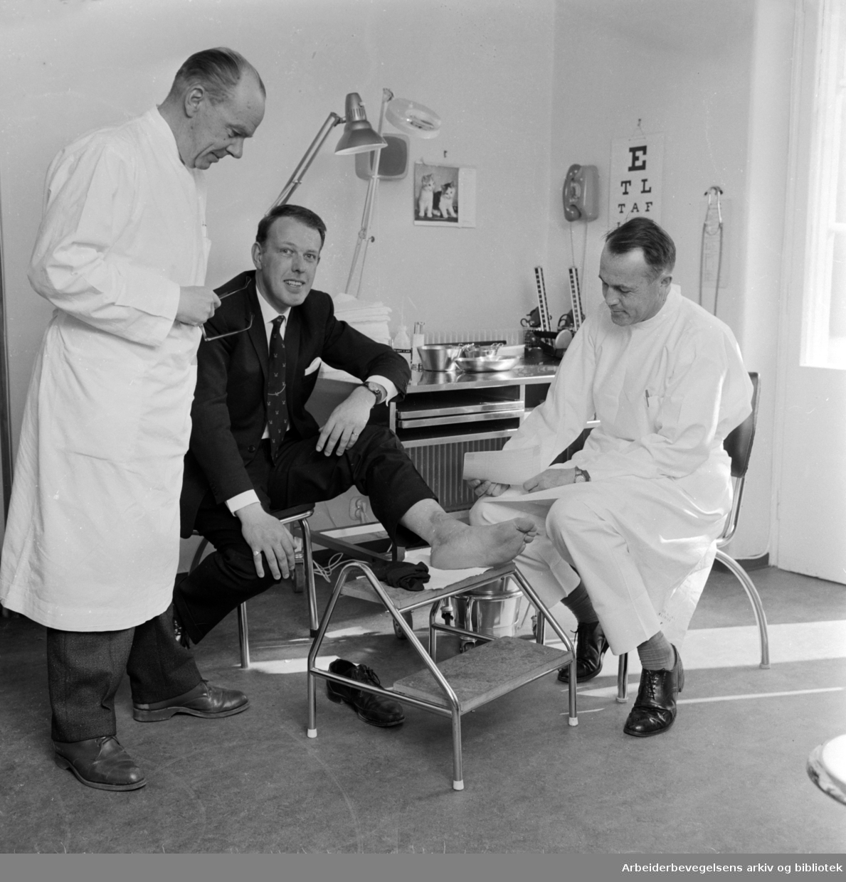 Røde Kors legevakt. Sykehusdirektør Ragnar Nordlie (tv)og behandlende lege, Einar Gjersøe, undersøker foten til pasient D. Sanderson fra Newcastle. Mai 1966