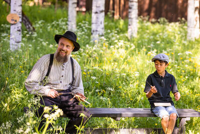 En tunvert sitter på en benk i høyt gress ogs pikker sammen med en gutt.